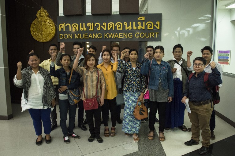 Migrant workers from Myanmar gesture defiantly for the media before entering court to face defamation charges by a Thammakaset chicken farm, after they accused the company of labor abuses, at Don Muang Magistrates Court in Bangkok on Feb. 7, 2018. / AFP PHOTO / LILLIAN SUWANRUMPHA