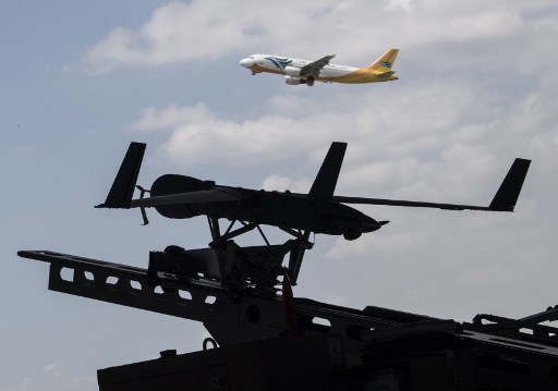 A ScanEagle Umanned Aerial Vehicle, is displayed on its launcher while a Cebu Pacific passenger plane flies by. Photo by AFP/Ted Aljibe