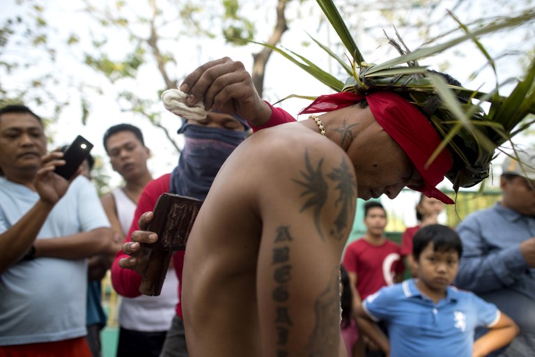 Flagellant RJ Rivera has his back wounded to bleed as part of his penitence during the re-enactment of the crucifixion of Jesus Christ for Good Friday celebrations ahead of Easter in the village of San Juan, Pampanga, north of Manila on March 30, 2018.
Rivera, a 33-year-old construction worker, has been a flagellant for 11 straight years and said he does it for the sake of his wife, who is working in Saudi Arabia, and his two daughters and son. / AFP PHOTO / Noel Celis