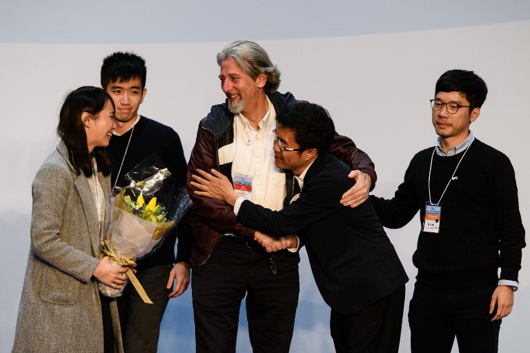 Pro-democracy candidate Au Nok-hin (2ndR) is congratulated by disqualified lawmaker Nathan Law (R), disqualified candidate Agnes Chow (L) and defeated pro-democracy candidate Paul Zimmerman (C) after Au won the Legislative Council by-election for the Hong Kong Island constituency in Hong Kong early on March 12, 2018. / AFP PHOTO / Anthony WALLACE