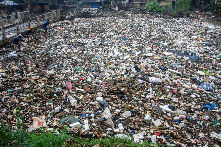 Villagers search for recyclable waste as they stand on top of floating garbage covering the Citarum river in Bandung, West Java province on March 3, 2018. AFP PHOTO / Timur Matahari 