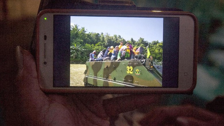 A colleague of a victim showing a photo of children and teachers sitting on an M113 Armored Personnel Carrier belonging to the Indonesian Military. Photo: Antara Foto/Andreas Fitri  Atmoko