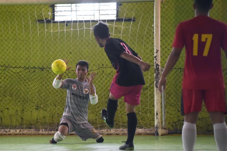 This picture taken on February 3, 2018 shows goalkeeper Eman Sulaeman (L) attempting a save during a futsal (five-a-side indoor football) match in Indramayu, West Java. 
When Eman Sulaeman begged his parents to let him play football, the couple worried their young son — born with no feet and just one full leg — would be mocked. But two decades later, the 30-year-old Indonesian goalkeeper is wowing crowds at home and abroad with his “cat-like” reflexes, and knocking home a powerful message about people with disabilities. AFP PHOTO / ADEK BERRY