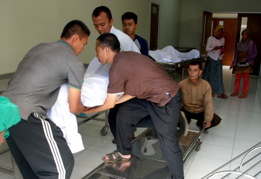 Indonesian medical staff place the bodies of the victims who died from drinking illegal alcohol, at a hospital in Bandung, West Java province on April 9, 2018. 
More than 60 Indonesians are dead and dozens have been hospitalised from drinking illegal homemade alcohol, authorities said, with the toll steadily climbing. / AFP PHOTO / Timur Matahari