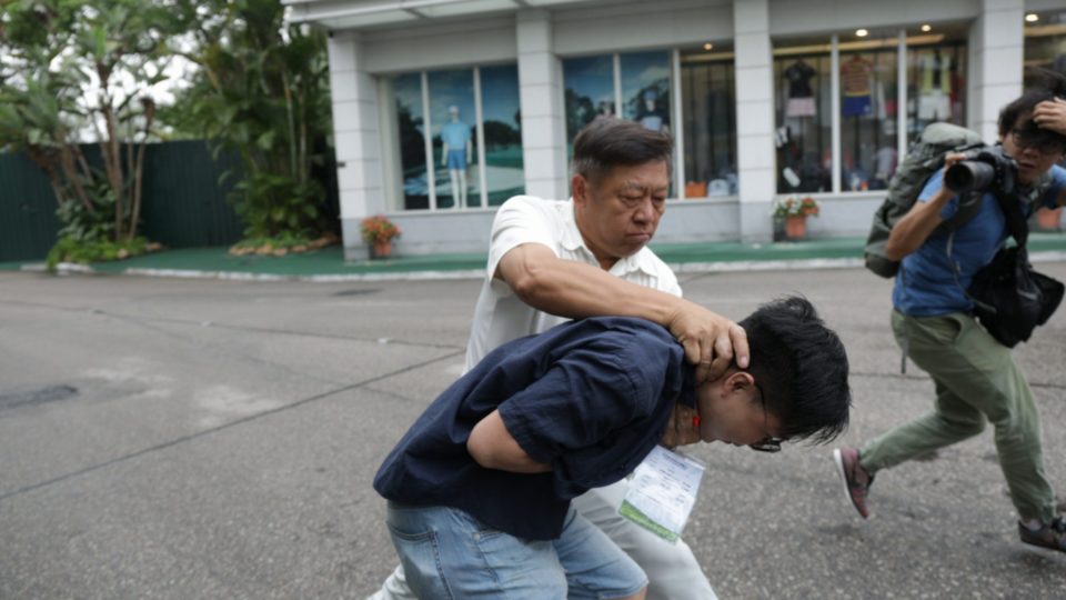 A protestor being grabbed by the neck by a member of the Hong Kong Golfing Alliance. Photo via Facebook.