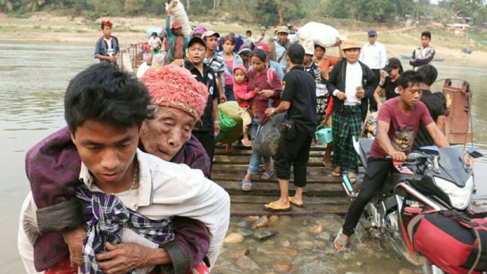 114-year-old Sutna Hkawn Bu flees her village on the back of her grandson Ma Tang during military offensives in Injangyang, Kachin State, on April 26. Photo: ZRH / Kachin Times