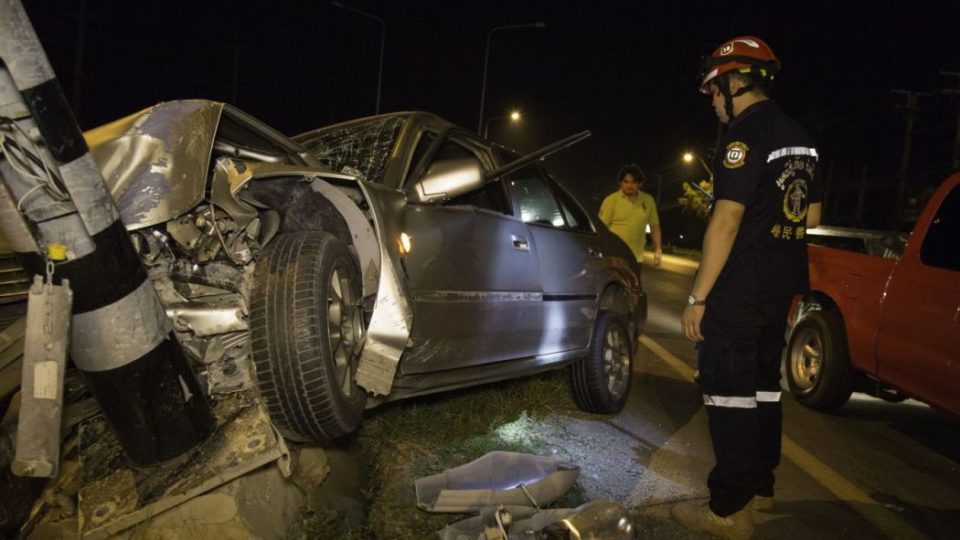 A Romsai rescue worker inspects a car crash on the side of a highway on the fifth night of Songkran 2015. The drunk driver was speeding and crashed his car head on into a light pole. Photo: Alexander Hotz/ Coconuts Media
