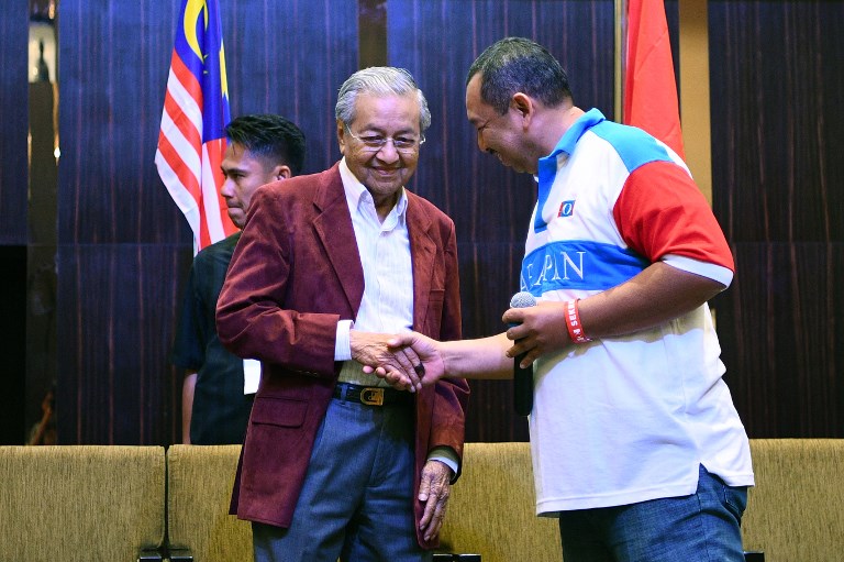 Former Malaysian prime minister and opposition candidate Mahathir Mohamad (L) is being congratulated during a press conference in Kuala Lumpur on early May 10, 2018.
Malaysia’s opposition alliance headed by veteran ex-leader Mahathir Mohamad, 92, has won a historic election victory, official results showed on May 10, ending the six-decade rule of the Barisan Nasional (BN) coalition.  / AFP PHOTO / Manan VATSYAYANA