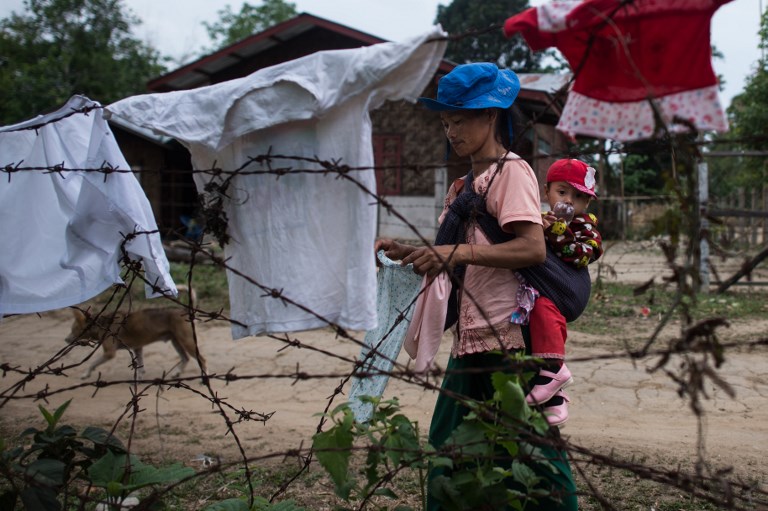 In this picture taken on May 13, 2018, an internally displaced woman with a child hangs laundry outside a temporary shelter at a church compound in Myitkyina, Kachin state. / AFP PHOTO / Ye Aung THU