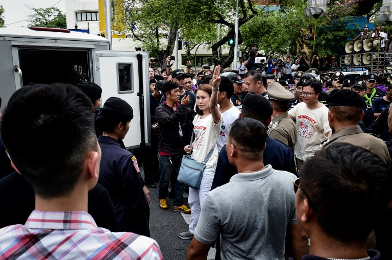 A protest leader makes a hand salute while led away by police to a van during a demonstration to mark the fourth year of junta rule in Bangkok on May 22, 2018.
Thai police detained leaders of an anti-junta protest on May 22 who had tried to mark the fourth anniversary of a coup by marching to Government House, one of the largest acts of dissent since the army grabbed power. / AFP PHOTO / Lillian SUWANRUMPHA