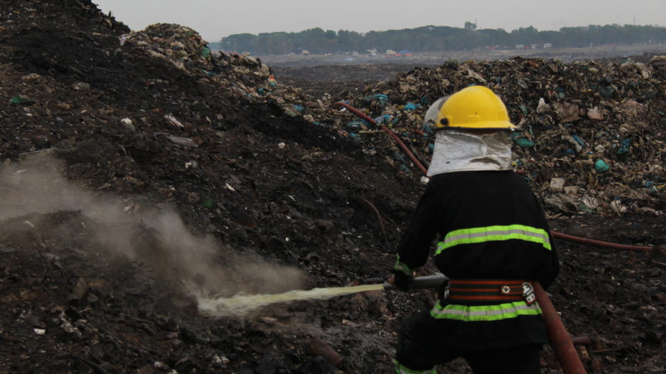A firefighter sprays water at a plume of smoke rising from the ground inside the Htein Bin landfill on May 3, 2018.