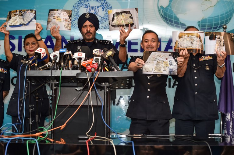 Members of the Malaysian Police’s Commercial Crime Investigation Department (CCID) hold up pictures of seized items while addressing media in Kuala Lumpur on June 27, 2018.
Items seized from six premises linked to ousted Malaysian leader Najib Razak, including cash, a vast stash of jewellery and luxury handbags, are worth up to 273 million USD, police said on June 27. / AFP PHOTO / Mohd RASFAN