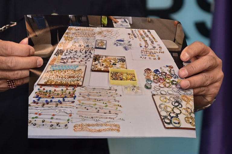 A member of the Malaysian Police’s Commercial Crime Investigation Department (CCID) holds up a picture of seized items while addressing the media in Kuala Lumpur on June 27, 2018.
Items seized from six premises linked to ousted Malaysian leader Najib Razak, including cash, a vast stash of jewellery and luxury handbags, are worth up to 273 million USD, police said on June 27. / AFP PHOTO / Mohd RASFAN