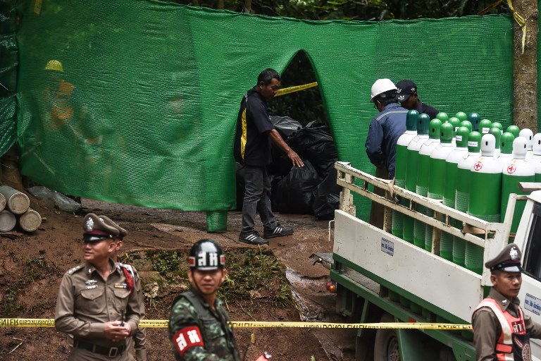 Rescue workers move air tanks at the Tham Luang cave area as operations continue for the 12 boys and their coach trapped at the cave in Khun Nam Nang Non Forest Park in the Mae Sai district of Chiang Rai province on July 8, 2018.
Thai authorities told media on July 8 to leave a camp site near the cave where 12 boys and their coach have been trapped for more than two weeks so that “victims” could be helped, possibly signalling a long-awaited rescue effort to get them out. / AFP PHOTO / LILLIAN SUWANRUMPHA