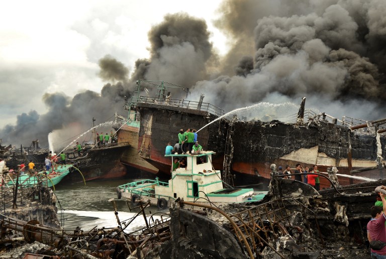 Indonesian workers and firefighters try to extinguish a fire on fishing boats at Benoa Harbor in Denpasar, Bali on July 9, 2018. A massive fire laid waste to dozens of boats at the port as firefighters battled to bring the dramatic blaze under control. Photo: Sonny Tumbelaka/AFP