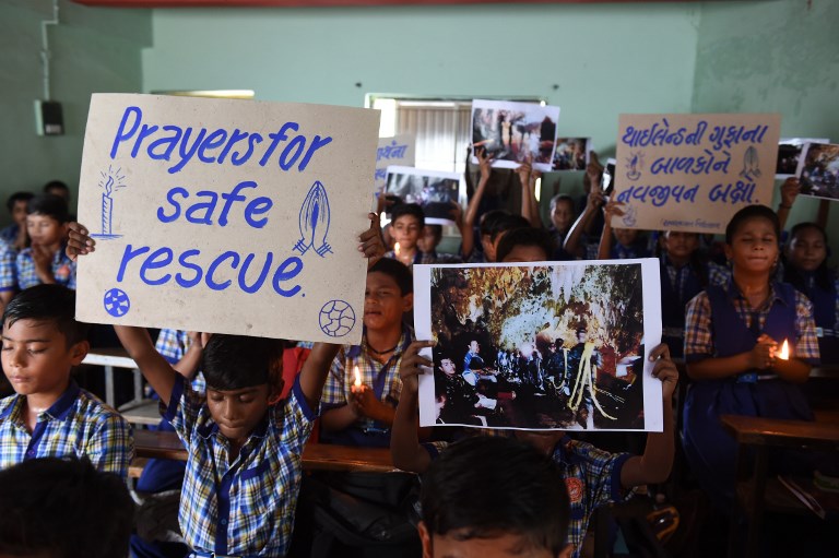 Indian schoolchildren hold placards and pictures during a prayer event for the safe rescue of young football players and their coach stuck in a cave in Thailand, in Ahmedabad on July 9, 2018.
Rescue workers dived deep inside a flooded Thai cave for a second straight day on July 9 in a treacherous bid to save a group of young footballers, with the mission chief promising more “good news” after four of the 13 were saved. Photo: AFP