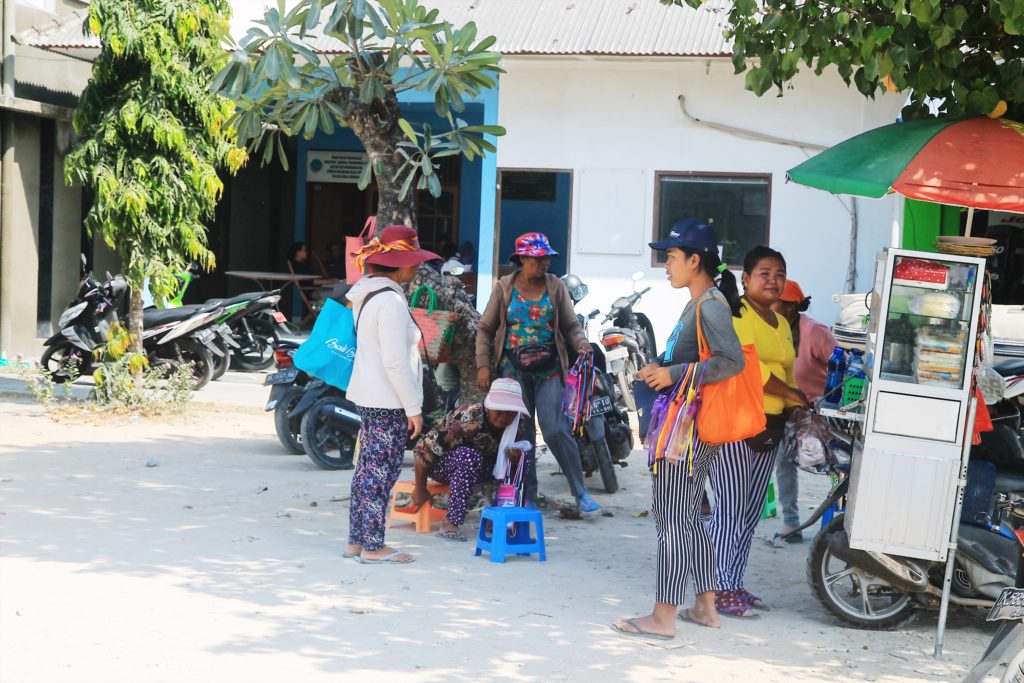 The ladies take cover in the shade while waiting for bus loads of tourists to unload at the jetty in Serangan. Photo: Jan Glenn/Coconuts Bali