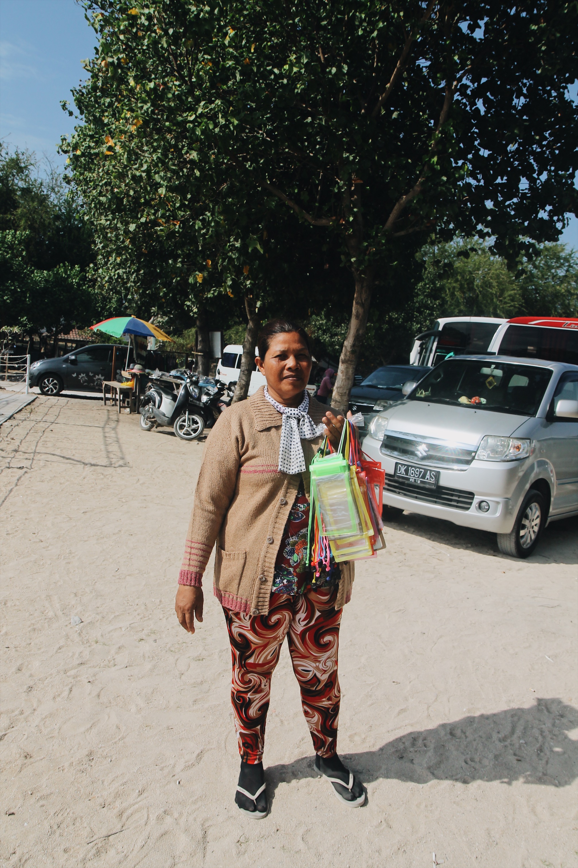 Bu Dedik sells the phone lanyards to tourists as they get on and off the fast boat in Serangan. Photo: Jan Glenn/Coconuts Bali