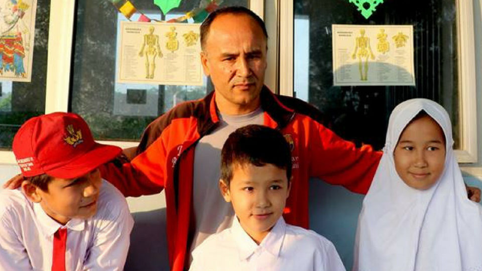 Three child refugees from Afghanistan stand with their father before attending school at a public school in Tangerang. Phote: International Organization for Migration