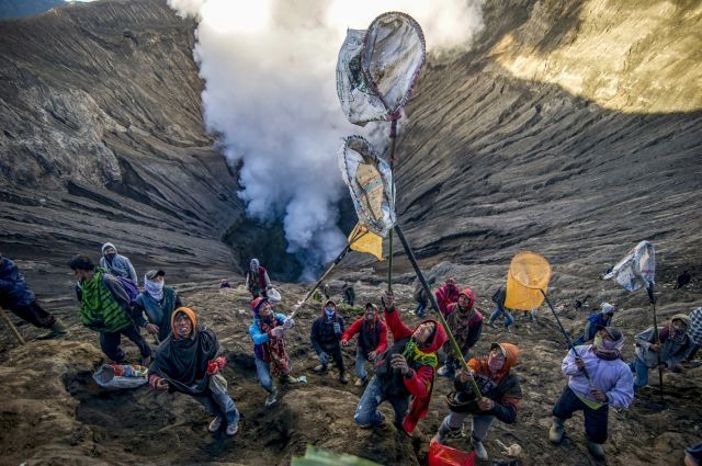 Other villagers — not members of the Tengger tribe — try to catch the offerings before they disappear into the billowing smoke using nets and sarong. This is not technically part of the ritual but reflects local frugal urges not to waste. PHOTO: AFP/JUNI KRISWANTO