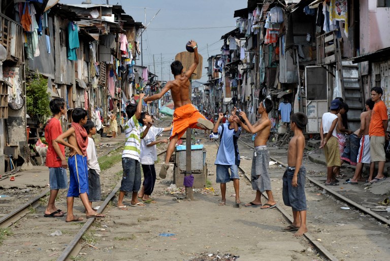 Children play basketball along railroad tracks bounded by shanty houses in Manila. (Photo: Jay Directo) 