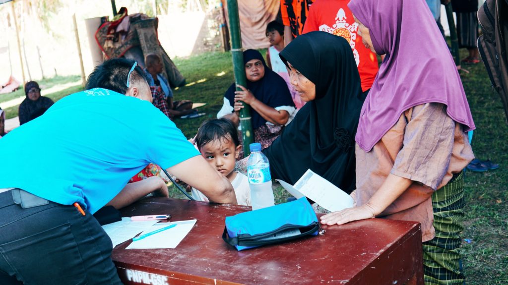 A young girl is examined by a volunteer doctor from the Bumi Sehat team at an evacuation camp in West Lombok. Photo: Coconuts Bali