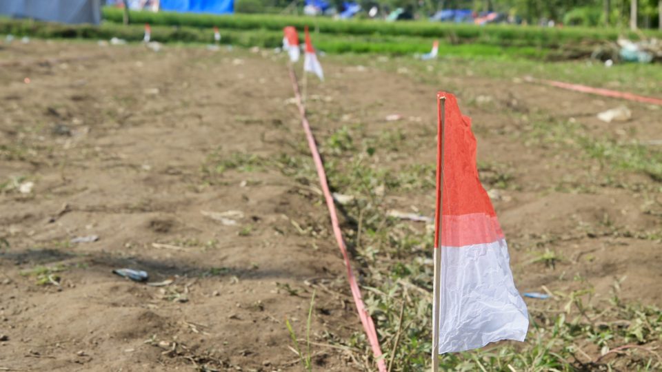 The Indonesian flag with a Lombok evacuee camp in the background. Photo: Coconuts Bali