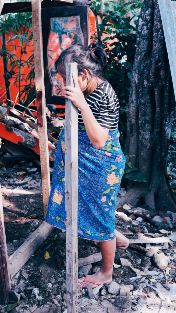 Dini, a resident of a village in Gunung Sari, navigates a path through the rubble. She is eight months along, carrying twins. Photo: Coconuts Bali