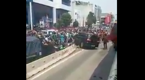 A car stuck on a busway lane separator after the driver tried to escape mob justice in West Jakarta. Photo: Twitter/@JakartaHeadline