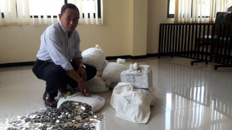 Dwi Susilarto’s lawyer Sutarto showing the court his client’s payment in small coins. Photo: Sutarto