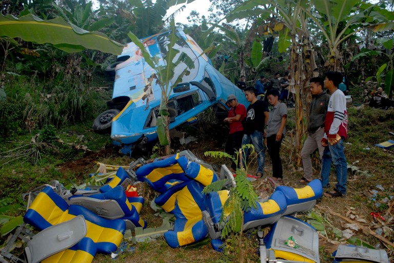 Indonesian people look at the wreckage of a bus after it crashed and plunged into a ravine in Sukabumi region, West Java on September 8, 2018. 
At least 21 people died and several others were injured when a bus carrying domestic tourists crashed and plunged into a ravine on the Indonesian island of Java, police said on September 8. The crash happened when the bus with 37 people on board was heading to a holiday spot in Sukabumi region, West Java.  / AFP PHOTO / –