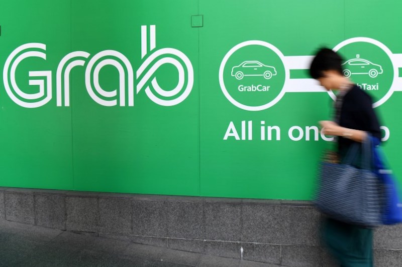 A woman walks past the Grab transport office in Singapore on September 24, 2018. Photo: Roslan Rahman / AFP