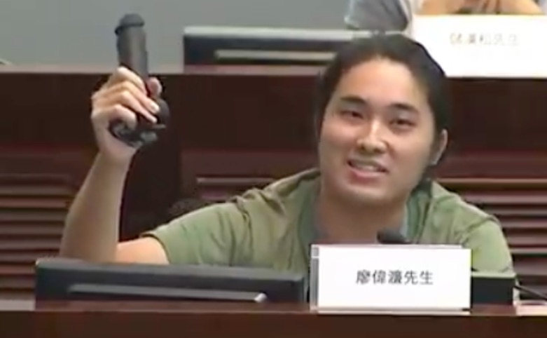 Demosistō standing committee member William Liu waving a dildo on a panel about land supply. Photo via Facebook video.