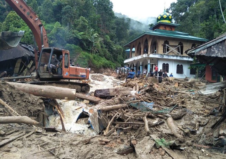 People use a heavy equipment to remove debris after flash floods hit the Saladi village in Mandailing Natal, North Sumatra on October 13, 2018. – At least 10 people are dead when heavy rain led to flash floods and landslide in Indonesia, an official said on October 13. (Photo by AGUS SALIM / AFP)