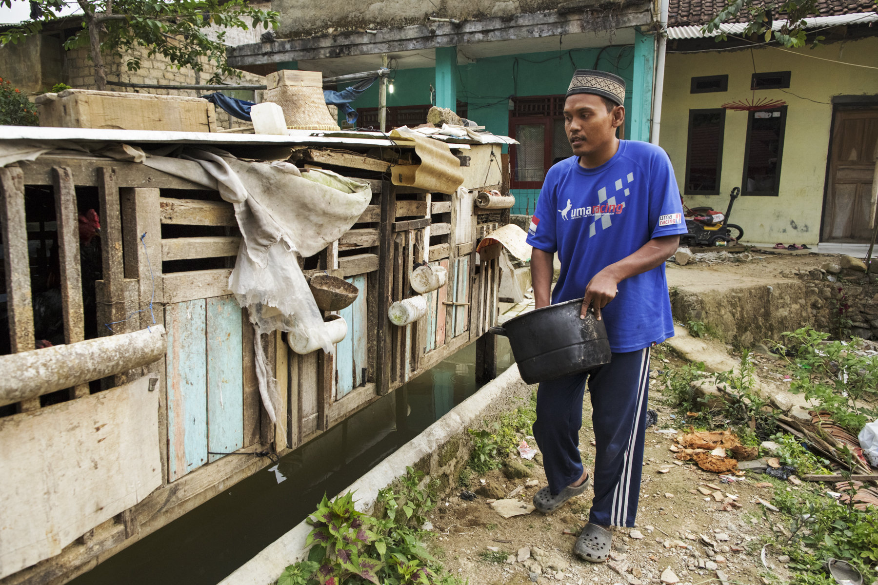 Asep, a 34-year-old man with a psychosocial disability whom his family chained for three years, feeds chickens outside his family home in Banjarsari village in Ciawi, Bogor. Photo: Andrea Star Reese for Human Rights Watch