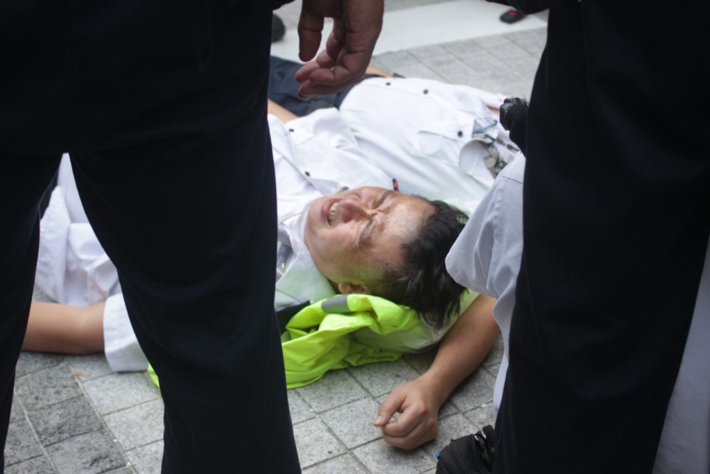 Security guard at the Central Government Office on the floor following a scuffle with protesters.