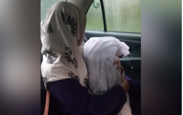 Noraihan Ab Aziz holding the body of her daugher, Nur Muarzara Ulfa Muhammad Zainal via Facebook/Berita Harian