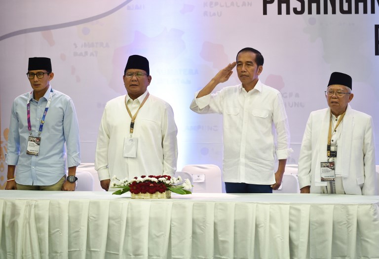 President candidates incumbent President Joko Widodo (2nd R) and Prabowo (2nd L) and vice president candidates Maruf Amin (R) and Sandiaga Uno (L) sing Indonesia’s national anthem before the draw for 2019 presidential election at election commission office in Jakarta, on September 21, 2018. (Photo by BAY ISMOYO / AFP)