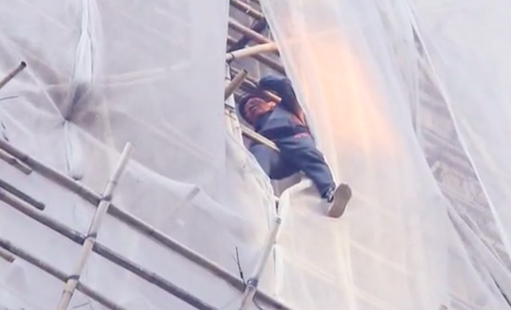 A Vietnamese woman sits on some bamboo scaffolding on a high-rise building in Causeway Bay. Screengrab via Apple Daily video.
