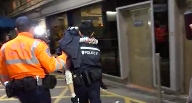 A police officer carrying the young daughter of a woman who was stabbed by her boyfriend last night. Screengrab via Apple Daily video.