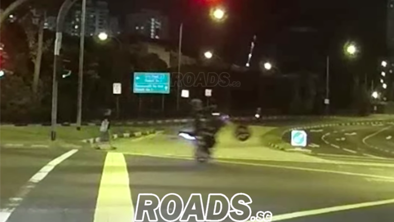 An e-biker is seen pulling off a wheelie at a Clementi junction before falling off his bike (Photo: ROADS.SG / Facebook)