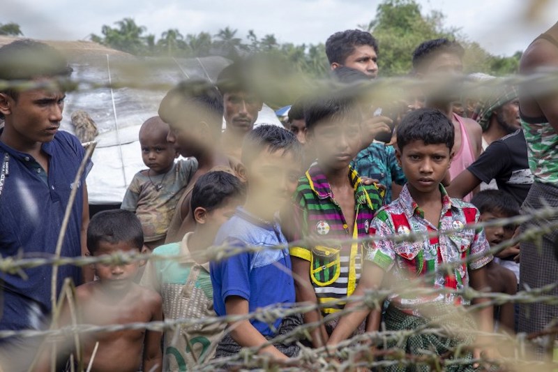 In this file photo taken on August 24, 2018 Rohingya refugees gather near the fence in the “no man’s land” zone between Myanmar and Bangladesh border as seen from Maungdaw, Rakhine state during a government-organized visit for journalists. (Photo by Phyo Hein KYAW / AFP)