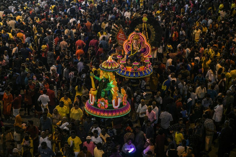 This picture taken on January 20, 2019 shows hundreds of Hindu devotees making their pilgrimage to a Batu Caves temple during Thaipusam festival celebrations at a complex of temples outside Kuala Lumpur. - Malaysian Hindu devotee Kumaraguru Kunalan hauled a wooden pole with metal pots hanging from it up to a temple carved into a hillside as drumming and incense smoke filled the air. (Photo by MOHD RASFAN / AFP)