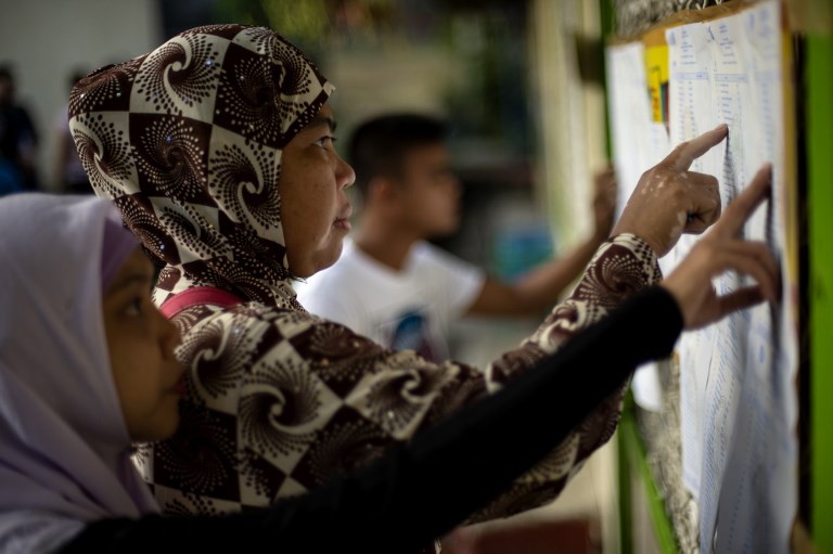 Muslim women look for their names at a voting precinct in Maguindanao, on the southern island of Mindanao on January 21, 2019, the plebiscite to ratify the passage of the Bangsamoro Organic Law (BOL). – A decades-long push to halt the violence that has claimed some 150,000 lives in the southern Philippines culminates with a vote on giving the nation’s Muslim minority greater control over the region. (Photo by Noel CELIS / AFP)