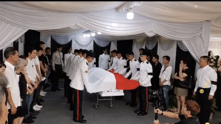 The Singapore flag was placed over Aloysius Pang’s coffin by military servicemen (Photo: Video screengrab from Noontalk Media / Facebook)