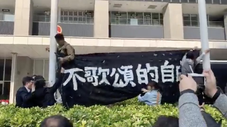 Demosisto members hang a banner on the flag poles on Civic Square protesting a controversial national anthem law. Screengrab via Facebook video/Demosisto.