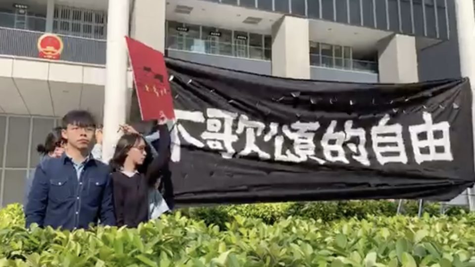 Pro-democracy activists Joshua Wong (left) and Agnes Chow (right) protest the national anthem law at Civic Square outside the Central Government offices. Screengrab  via Facebook video/Demosistō.