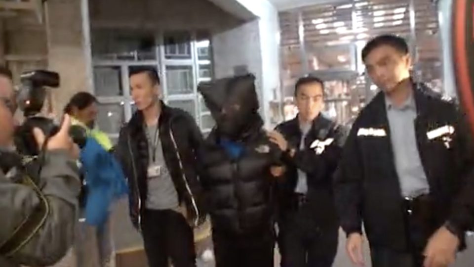 Police apprehend a 36-year-old man surnamed Hau who almost completely severed off the ear of his girlfriend’s ex. Screengrab via Apple Daily video.