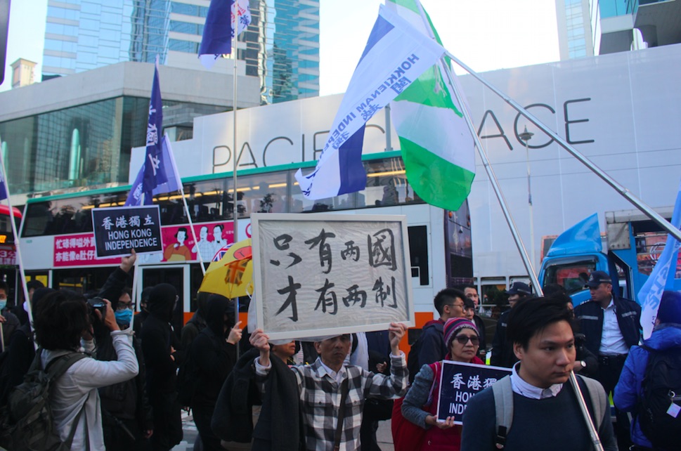 A man holds a placard that reads: "Only with two countries will there be two systems." Photo by Vicky Wong.
