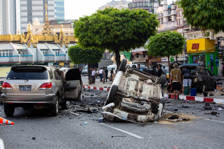 This photo taken on February 26, 2019 shows production crew setting up a street scene with damaged vehicles during the filming of the movie “Line Walker 2” near a pagoda in Yangon. – Cars dangling from cranes, street shoot-outs and actors rappelling from roofs — Yangon residents were transfixed this week by the filming of a big-budget Hong Kong action movie around the city’s iconic Sule pagoda. (Photo by Sai Aung MAIN / AFP)